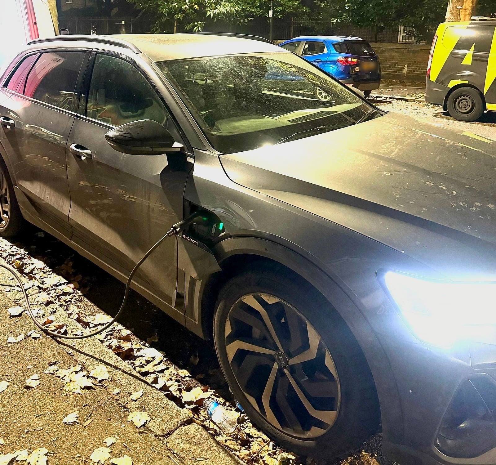 A grey electric SUV on charge under a street light