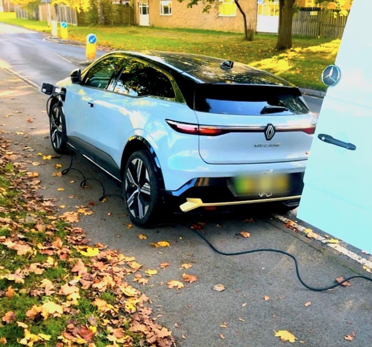 A Renault Megane E-Tech on charge at the kerb on an autumn morning, our van parked beside it